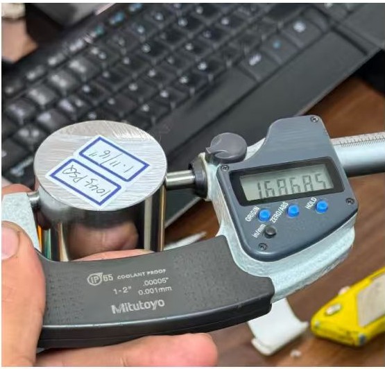 Medición del diámetro de una barra redonda de acero con calibre, verificando tolerancias dimensionales